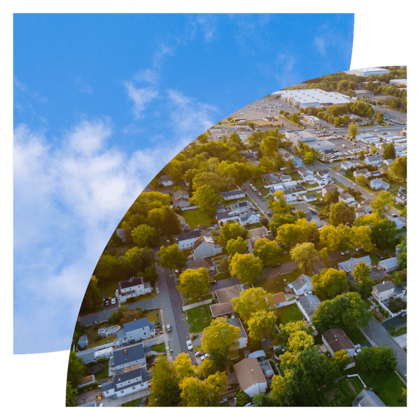 An aerial view of a neighborhood layered on top of an image of a partly-cloudy sky.